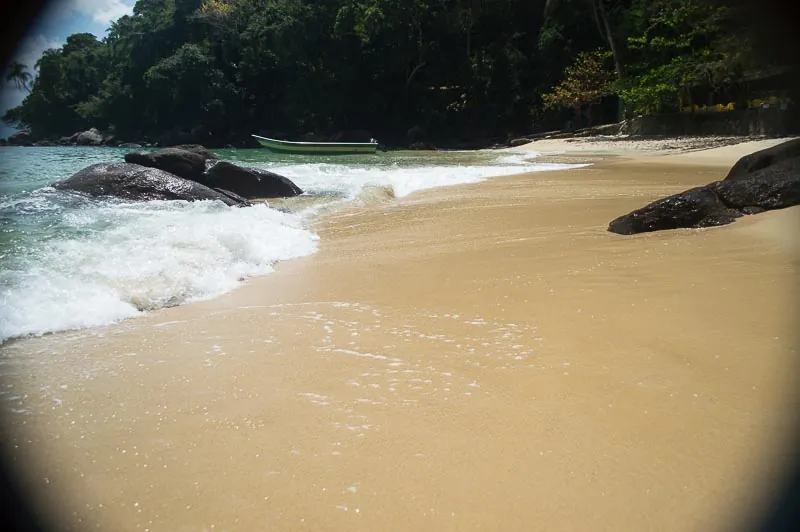 Faixa de areia da Ilha das Couves, em Ubatuba, com mar entrando entre as pedras