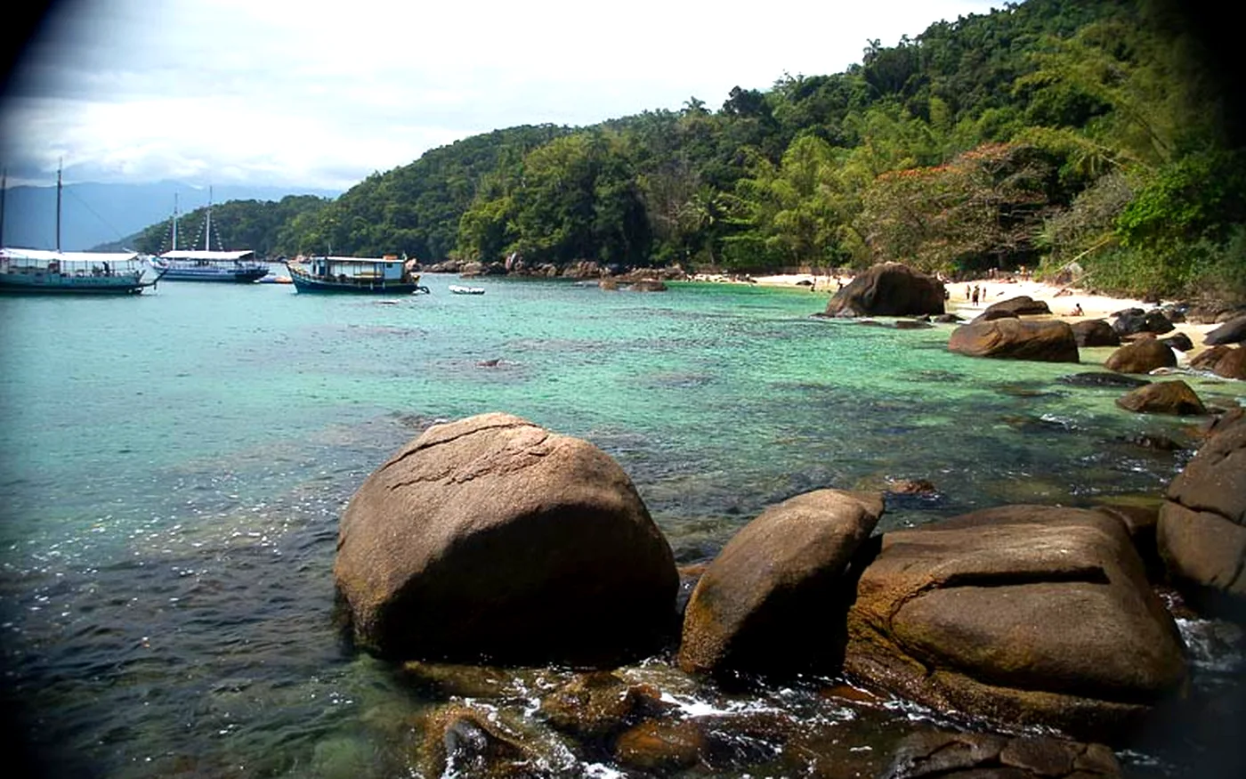 Enseada da Ilha das Couves com água turquesa, pedras e barcos ancorados